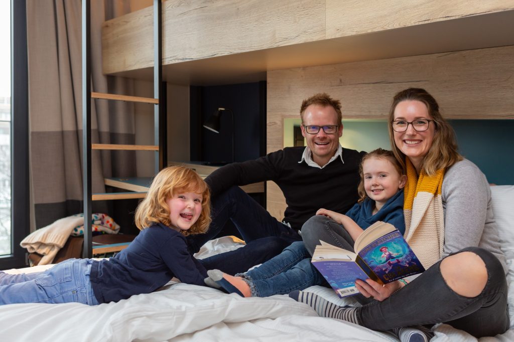 Familien auf einem Bett im Hotelzimmer des Schulz Hotels Berlin Ostbahnhof